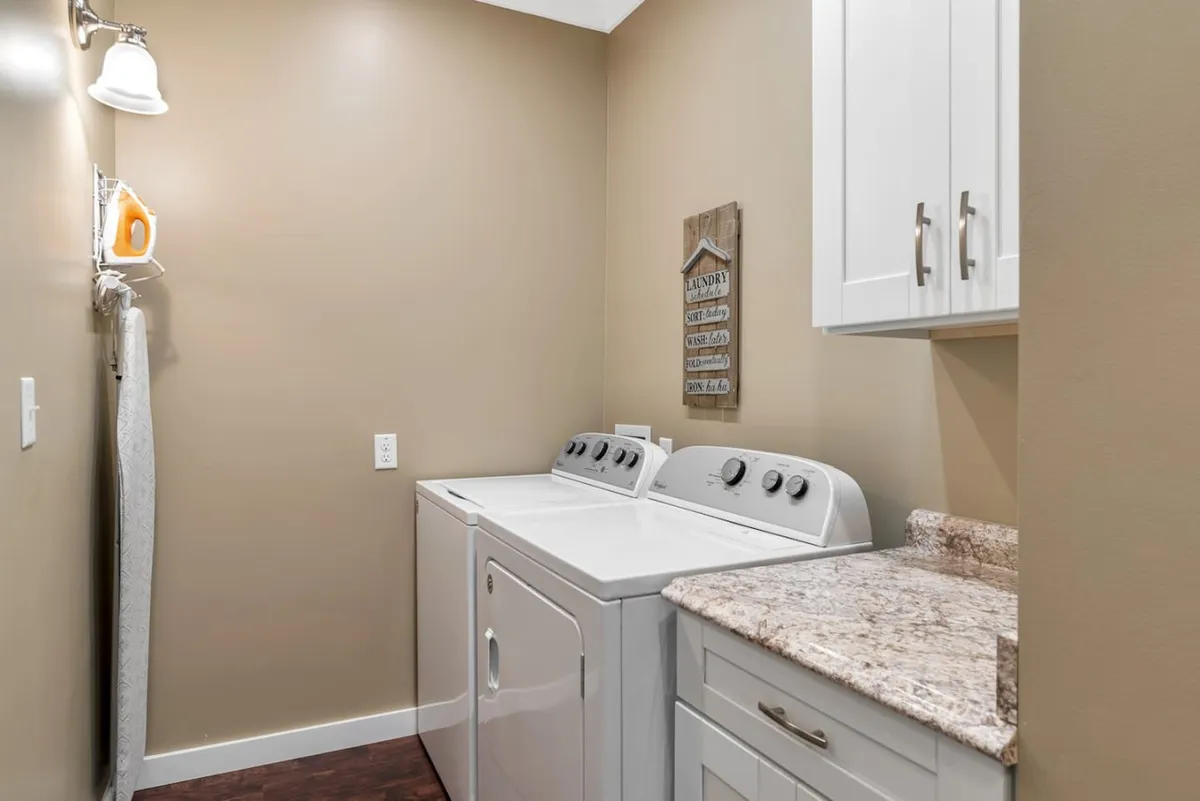 A thoughtfully organized laundry area with a modern washing machine and dryer, granite countertop, and a decorative sign. The clean lines and practicality evoke a sense of comfort and convenience for families traveling together.